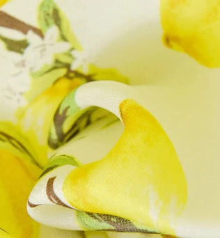 Image montrant un tissu imprimé avec des motifs de citrons jaunes vifs et des détails floraux, idéal pour des projets créatifs et décoratifs.