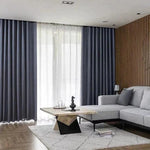 Rideaux élégants dans un salon moderne et épuré, parfaits pour créer une ambiance chaleureuse et raffinée. Idéal pour ceux qui cherchent à embellir leur intérieur avec style. Meuble d'angle gris confortable, posé sur un tapis clair, apporte une touche de confort à l'espace de vie.