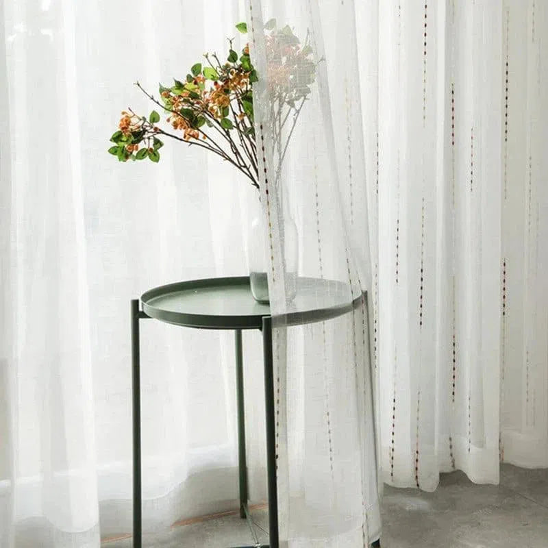 Table d'appoint moderne avec plateau vert, idéale pour le salon. Décoration élégante avec un vase rempli de fleurs séchées, placé contre des rideaux blancs translucides. Parfaite pour ajouter une touche naturelle et contemporaine à votre espace de vie.