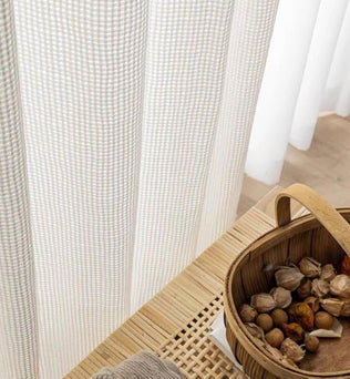 Rideaux à motifs géométriques élégants pour la décoration intérieure, présents dans un espace de vie éclairé par la lumière naturelle ambiante. À côté, un panier en osier contenant des éléments décoratifs naturels, idéal pour ajouter une touche rustique à votre maison. Solution parfaite pour embellir votre intérieur et créer une atmosphère cosy.