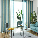 Salon moderne avec rideaux bleu-vert, décoration épurée et plantes vertes; ambiance lumineuse et accueillante; mobilier contemporain incluant un canapé turquoise, une table basse ronde et des chaises design; intérieur idéal pour un espace de vie serein.