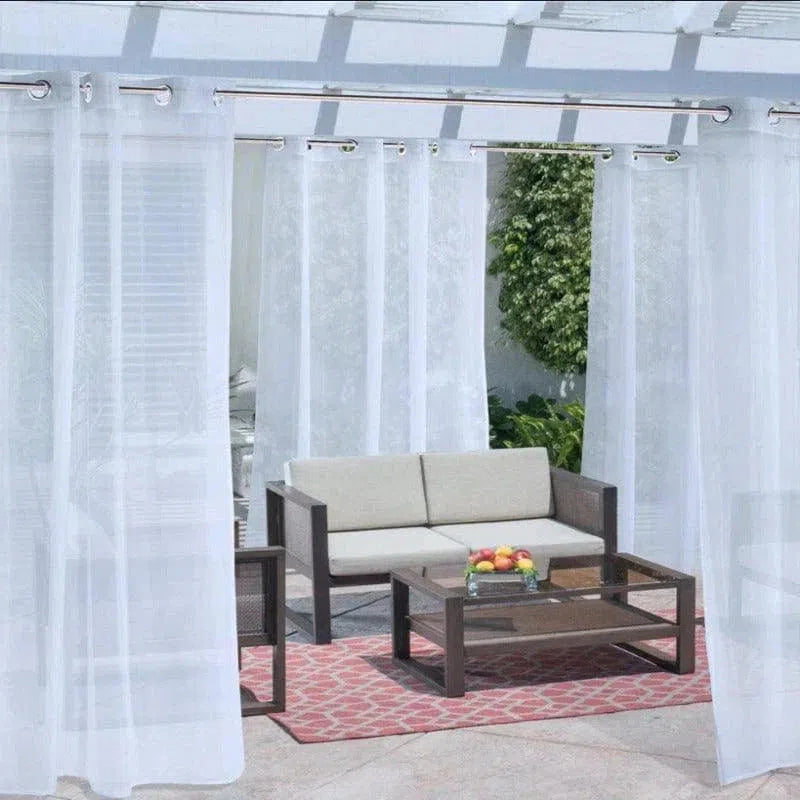 Salon de jardin élégant avec rideaux blancs transparents, canapé moderne et table basse, idéal pour créer un espace extérieur confortable et accueillant.