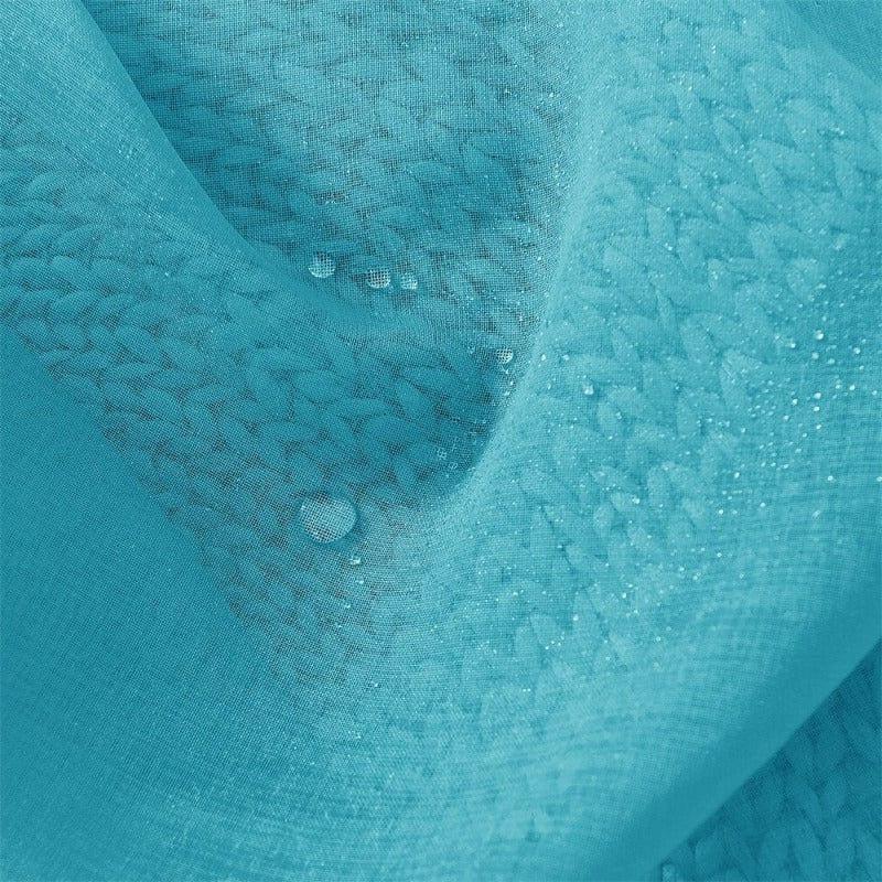 Gros plan sur un tissu bleu avec un motif texturé, montrant des gouttes d'eau reposant à sa surface, illustrant sa résistance à l'eau et son design élégant.