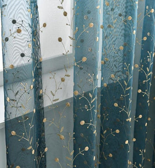 Voilage décoratif bleu brodé de motifs floraux dorés, idéal pour habiller élégamment les fenêtres du salon ou de la chambre. Ce rideau raffiné combine style moderne et allure naturelle, apportant une touche de sophistication à votre intérieur. Parfait pour créer une ambiance chaleureuse et accueillante dans toutes les pièces de la maison.