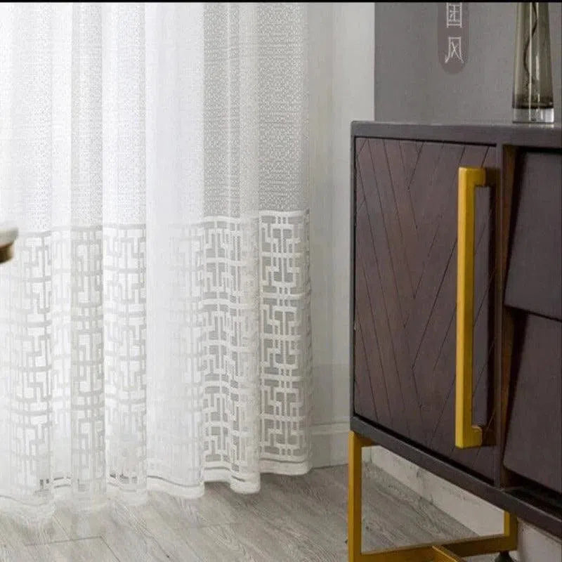Rideaux blancs élégants avec motifs géométriques transparents. Idéal pour ajouter une touche moderne et sophistiquée à votre salon ou chambre à coucher. Combinez le tout avec un meuble contemporain aux poignées dorées, parfait pour un intérieur chic et épuré. Embellissez votre espace de vie avec cette combinaison harmonieuse de design et de fonctionnalité.