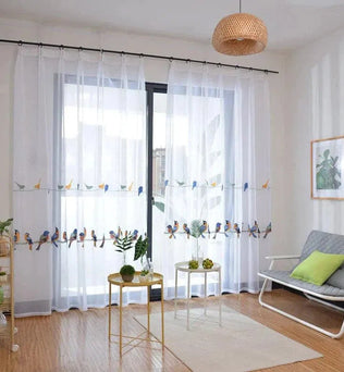 Rideau transparent blanc avec motifs d'oiseaux colorés, idéal pour ajouter une touche de nature et d'élégance à votre salon. Crée une ambiance lumineuse et aérée, parfait pour les espaces de vie modernes et accueillants. Accessoire décoratif tendance pour habiller une grande fenêtre ou une baie vitrée.