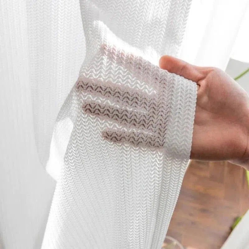 Voilage blanc de haute qualité pour intérieur moderne, filtrant la lumière tout en préservant l'intimité, parfait pour un salon lumineux et élégant.