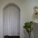Rideau embellissant une fenêtre arquée dans un intérieur élégant avec décoration végétale. Parfait pour ajouter une touche de raffinement et de charme classique à votre pièce. Idéal pour un salon ou une chambre, apportant une lumière douce et filtrée pour une atmosphère paisible.