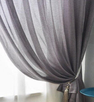 Rideau gris élégant pour salon moderne, suspendu à une fenêtre, offrant une ambiance chaleureuse. Idéal pour décorer votre intérieur tout en contrôlant la lumière. Accessoire chic pour un aménagement d'intérieur raffiné.