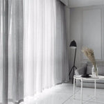 Rideaux blancs élégants pour salon moderne avec déco minimaliste, chaise grise confortable, lampe élégante et table basse design. Idéal pour un intérieur lumineux et contemporain.