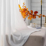 Voilage élégant blanc apportant une touche lumineuse et raffinée à une pièce, idéal pour filtrer la lumière tout en préservant l'intimité. Décoration intérieure accentuée par des feuilles automnales oranges, créant une ambiance chaleureuse. Convient parfaitement au salon ou à la chambre pour un style moderne et chic. Accessoire incontournable pour compléter votre décoration intérieure avec une touche naturelle.