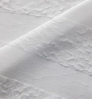 Texture élégante et finement détaillée d'un tissu blanc aux motifs délicats, parfait pour la décoration intérieure moderne et raffinée. Convient idéalement pour la confection de rideaux ou de voilages apportant une touche de légèreté et de sophistication à tout espace de vie.