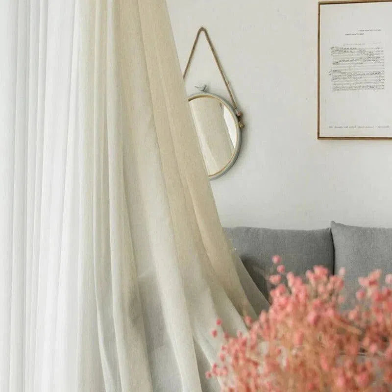 Rideau élégant et moderne dans un intérieur chic, parfait pour ajouter une touche de sophistication à votre salon. Avec un design épuré et une couleur neutre, ce rideau s'intègre harmonieusement dans tout style de décoration. Idéal pour créer une ambiance apaisante et lumineuse dans votre espace de vie. Accessoirisé avec un miroir rond et une décoration florale, il complète parfaitement un coin détente élégant.