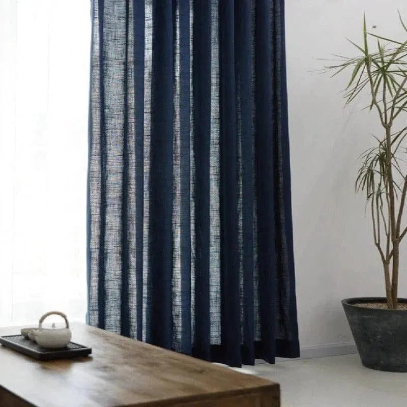 Rideau occultant bleu marine dans un intérieur moderne, idéal pour ajouter une touche élégante à votre salon. Le rideau est suspendu près d'une fenêtre, laissant passer la lumière tout en préservant l'intimité. Il se marie parfaitement avec une décoration minimaliste et des plantes d'intérieur.