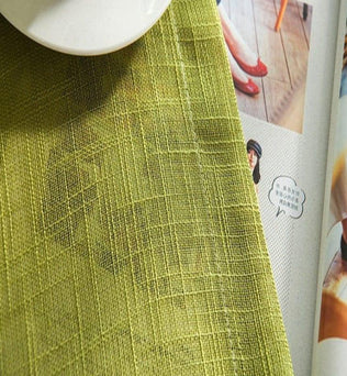 Produit textile vert posé sur une table avec un magazine ouvert en arrière-plan. Design moderne et élégant, idéal pour ajouter une touche de couleur à votre décoration intérieure. Accessoire parfait pour donner du style à votre maison.