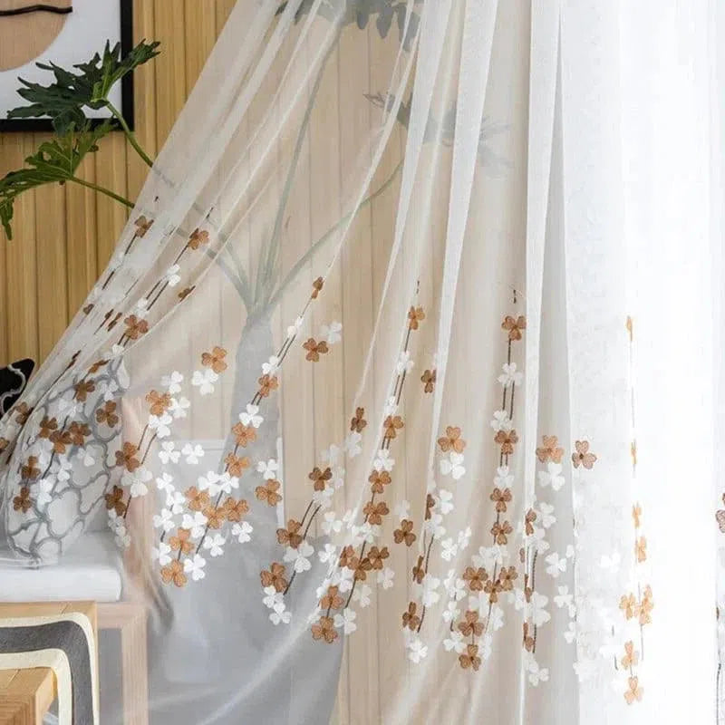 Voilage floral élégamment suspendu dans un intérieur moderne, orné de délicates fleurs marron et blanches, apportant une touche de fraîcheur et de style à votre décoration. Parfait pour habiller vos fenêtres avec légèreté et élégance.