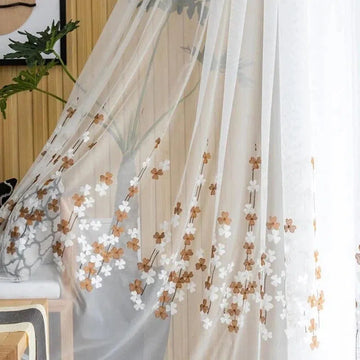 Voilage floral élégamment suspendu dans un intérieur moderne, orné de délicates fleurs marron et blanches, apportant une touche de fraîcheur et de style à votre décoration. Parfait pour habiller vos fenêtres avec légèreté et élégance.
