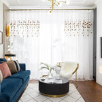 Rideaux de salon avec motifs de feuilles dorées, décoration intérieure moderne et élégante, parfaits pour ajouter une touche de raffinement à votre espace de vie. Éclairage sophistiqué et mobilier chic complètent l'atmosphère contemporaine.