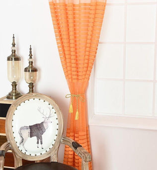 Chaise élégante avec motif de renne placée devant une fenêtre ornée de rideaux orange, accompagnée de deux lampes décoratives. Décoration intérieure moderne et chaleureuse, idéale pour un salon accueillant. Parfait pour apporter une touche originale et stylée à votre espace de vie.