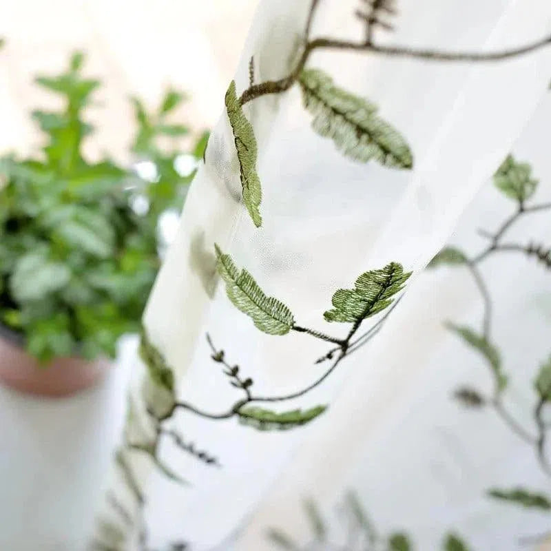 Voilage décoratif blanc avec motif brodé de feuilles vertes, idéal pour ajouter une touche naturelle et élégante à votre intérieur. Parfait pour les salons, chambres ou tout espace nécessitant une ambiance apaisante et lumineuse. Intégrez ce rideau tendance pour sublimer vos fenêtres tout en préservant la luminosité de vos pièces.