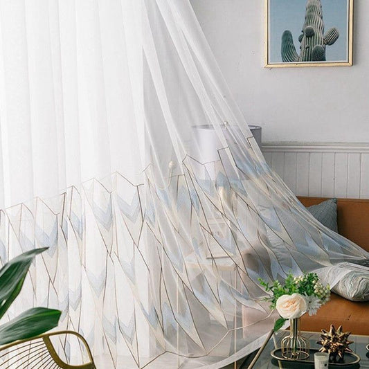 Voilage élégant avec motifs géométriques dorés, suspendu dans un salon lumineux et moderne, apportant une touche d'élégance et de luminosité à la décoration intérieure.