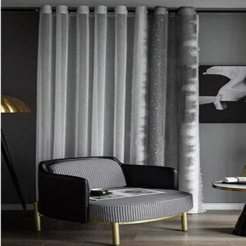 Fauteuil moderne élégant avec accoudoirs noirs, parfait pour un salon chic. Il est accompagné de rideaux gris et d'une lampe dorée, créant une atmosphère sophistiquée et contemporaine dans la pièce.