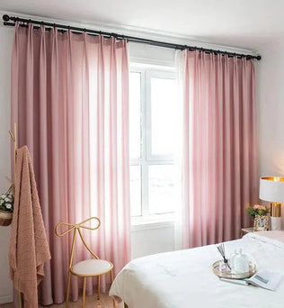 Rideaux roses élégants pour chambre à coucher moderne, apportant une ambiance douce et chaleureuse. Fenêtre lumineuse encadrée par des rideaux stylés, idéals pour un intérieur contemporain. Déco de chambre avec touches dorées et accessoires raffinés.