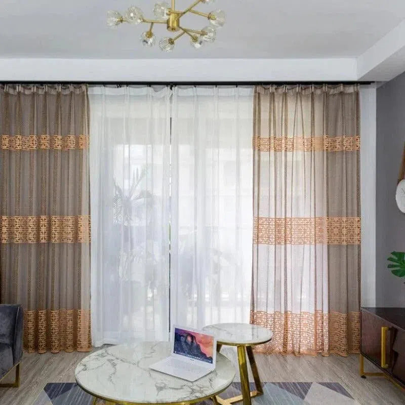 Paire de rideaux élégants aux tons neutres, habillant une grande baie vitrée dans un salon moderne. Les motifs ajourés ajoutent une touche décorative subtile, tandis que le design élégant procure une ambiance chaleureuse. Parfait pour apporter une lumière douce et tamisée dans votre espace de vie.