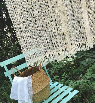 Décoration bohème avec un rideau crocheté élégant, accroché en extérieur. Ambiance naturelle et paisible avec un banc vert pastel et un panier tressé. Idéal pour créer un espace cosy dans votre jardin ou terrasse, apportant une touche d'élégance et de style artisanal à votre décoration extérieure.