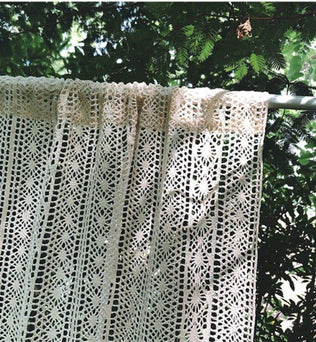 Rideau en dentelle crocheté à la main suspendu dans un jardin ensoleillé, idéale pour ajouter une touche bohème et élégante à votre décoration intérieure. Parfait pour une ambiance naturelle et lumineuse.