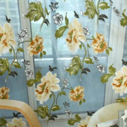 Rideau imprimé floral élégant pour le salon, avec des motifs de fleurs oranges et blanches sur fond bleu, ajoutant une touche de fraîcheur printanière à votre déco intérieure. Parfait pour apporter luminosité et style à votre espace de vie.