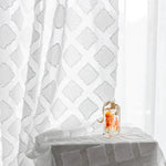 Sac à main transparent moderne avec motifs colorés, posé sur une table drapée d'un tissu à motifs géométriques, éclairé par une douce lumière naturelle. Accessoire tendance idéal pour un style élégant et contemporain, parfait pour les occasions spéciales ou un usage quotidien.