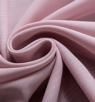 Tissu de couleur rose pastel drapé avec élégance, idéal pour la confection de vêtements délicats et projets de décoration intérieure raffinée.